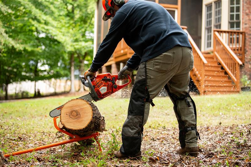 Mann der mit einer Husqvarna Motorsäge einen Baum auf einem Gestell schneidet