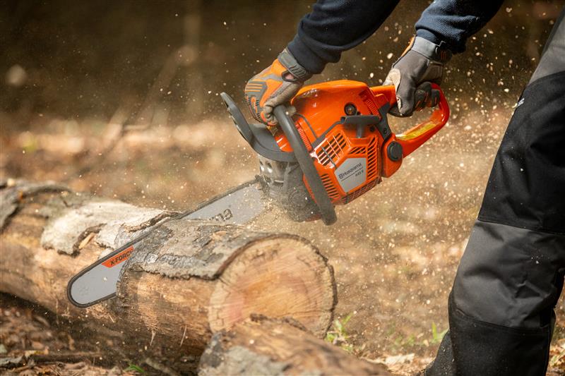 Mann der mit einer Husqvarna Motorsäge einen Baum schneidet (Nahaufnahme der Motorsäge)